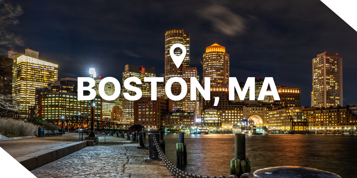 A nighttime skyline view of Boston, Massachusetts, with lit buildings, real estate properties, and a water view.