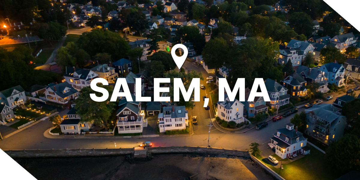 Aerial view of Salem, Massachusetts at night, featuring brightly lit real estate properties and tree-lined streets. 