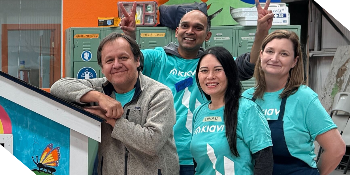 Four Kiavi employees, including CEO Arvind Mohan, pose with a colorful playhouse indoors, proudly showcasing the completed playhouse they helped Habitat for Humanity of Greater San Francisco build.