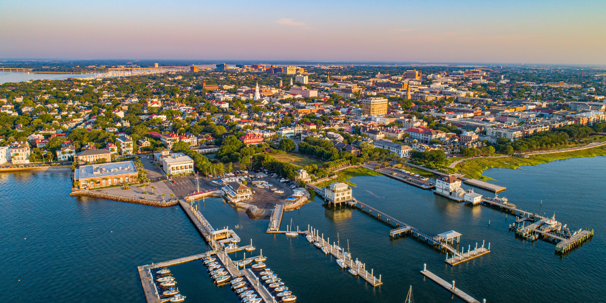 Aerial view of Charleston's historic downtown, coastal waterfront, and marina at sunset.