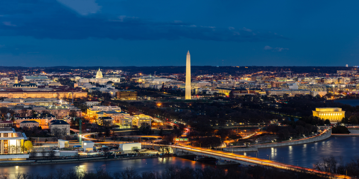 Nighttime panoramic view of Washington DC, highlighting the Washington Monument and Capitol building.