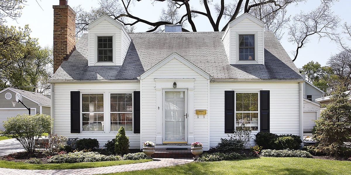 A pretty white rental property house with black shutters