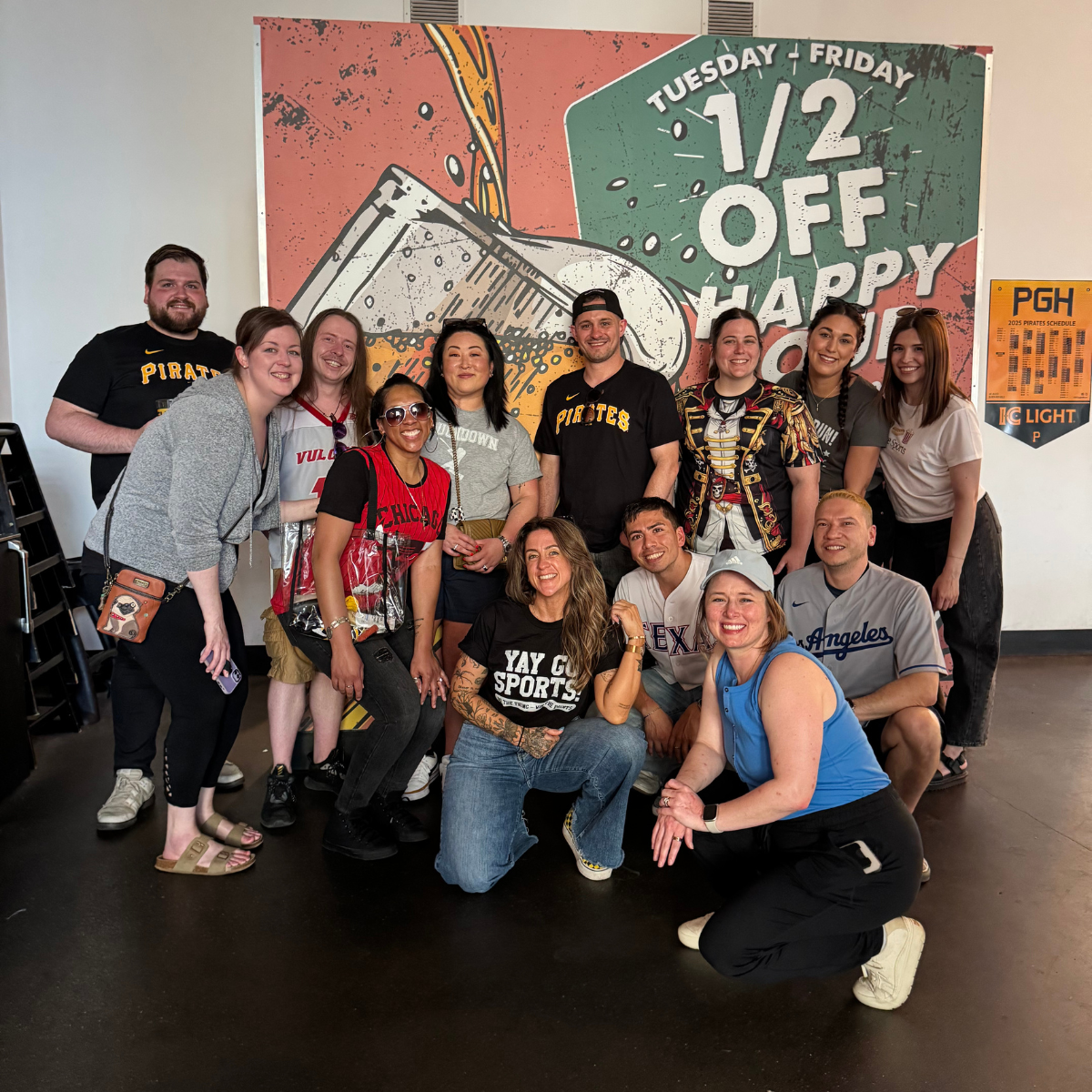 A group of 15 Kiavi employees posing for a photo in front of a colorful beer-themed background, all smiling.