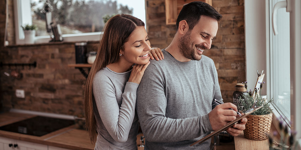 A smiling looking at a plan on a clipboard for a real estate investing project