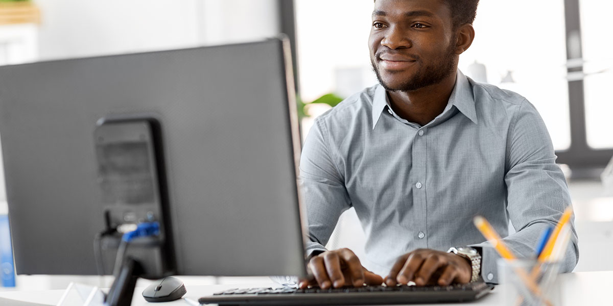 A man smiling at a desktop computer finding a fix and flip deal