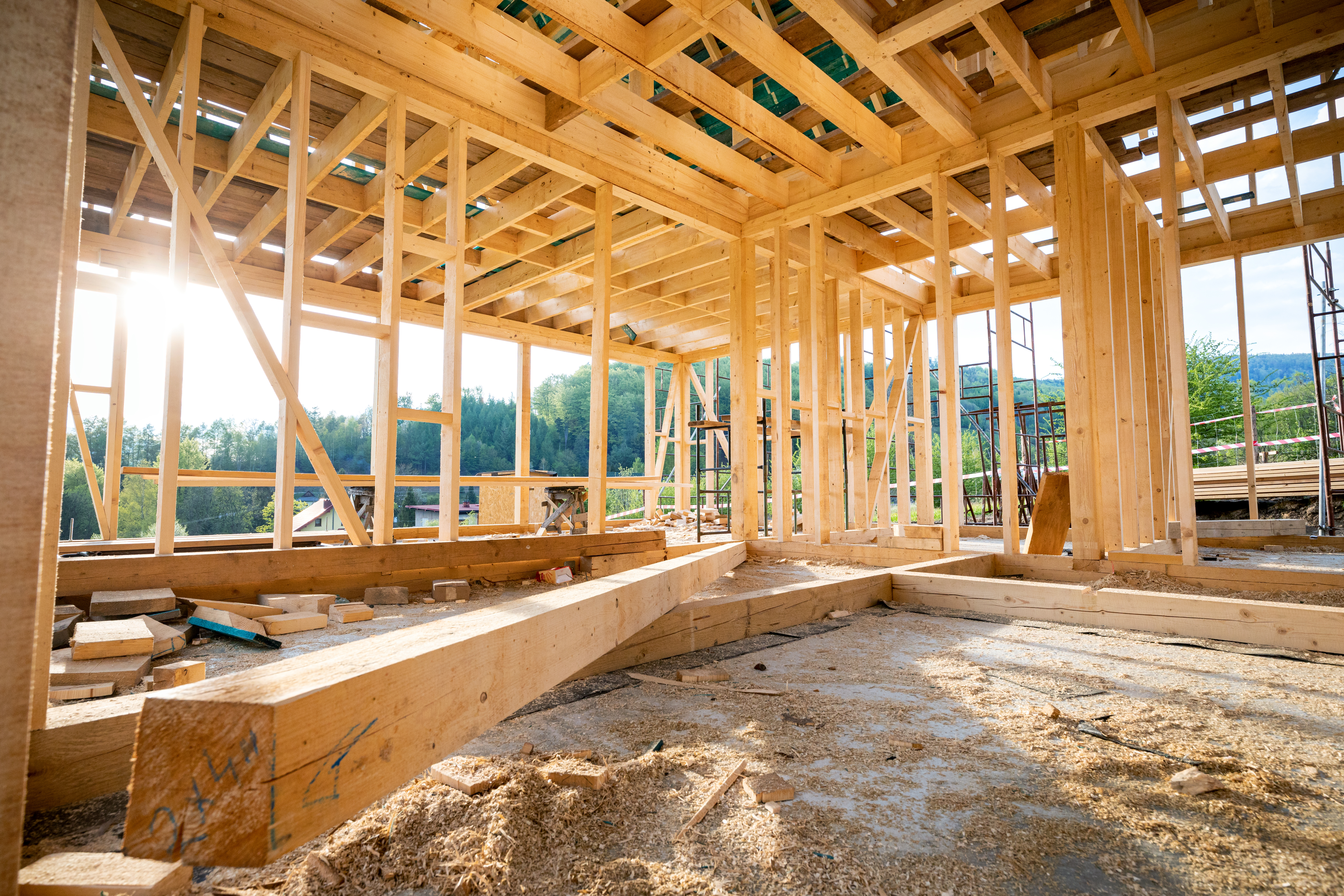 Interior of a wooden house under construction with sunlight shining through the frame.
