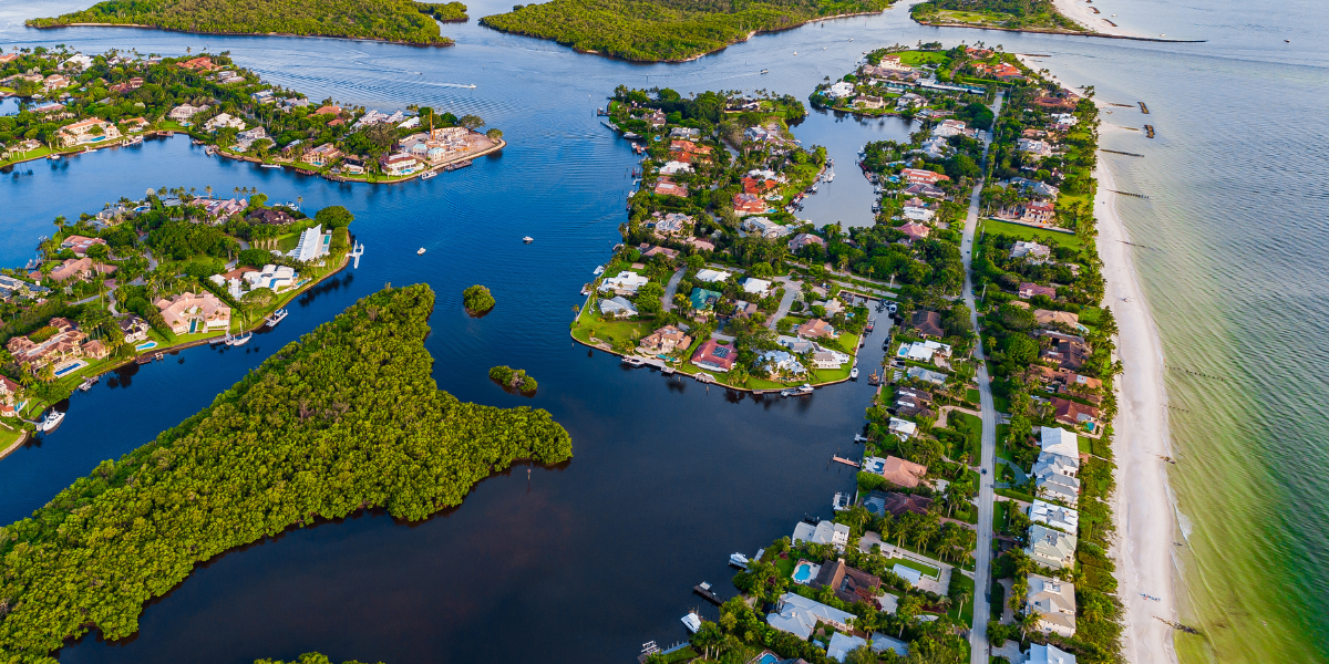 An aerial perspective of lush, affluent waterfront real estate investing properties in Florida and islands situated along a bright, vibrant coastline.