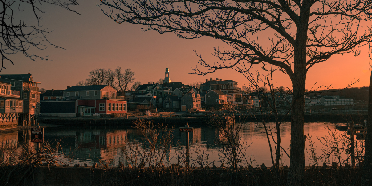 A sunset view of real estate in Salem, Massachusetts, featuring charming coastal real estate properties with vibrant exteriors and serene waterfront views.