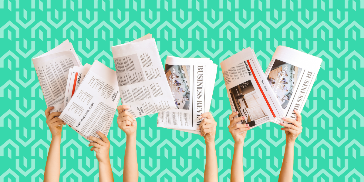 Six hands are raised, each holding a different business and finance newspaper against a teal background with a repeating geometric pattern, representing the July 2026 Kiavi real estate investing and financing market update.