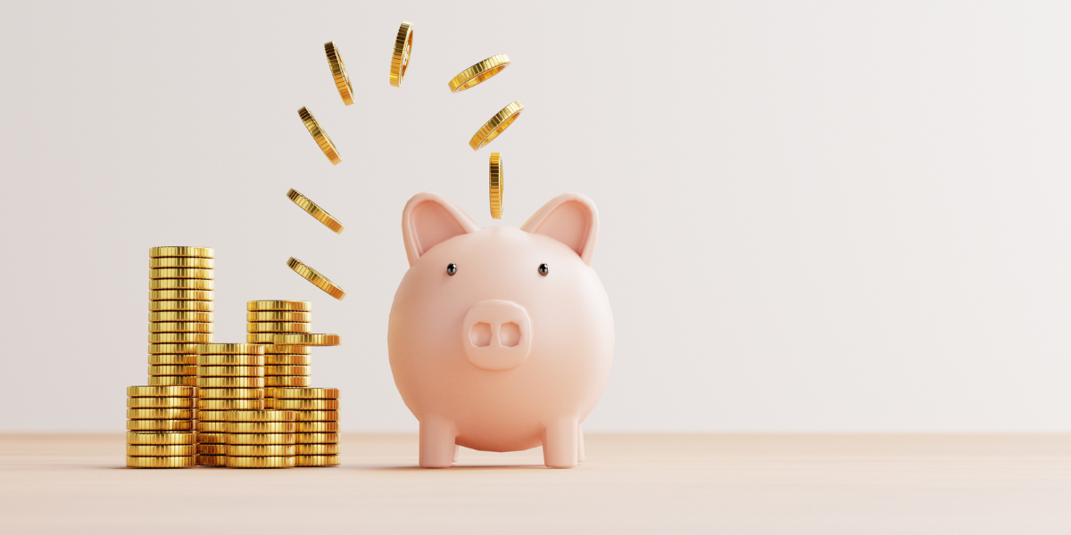 A pink piggy bank with stacks of gold coins next to it and individual gold coins falling into the top slot.
