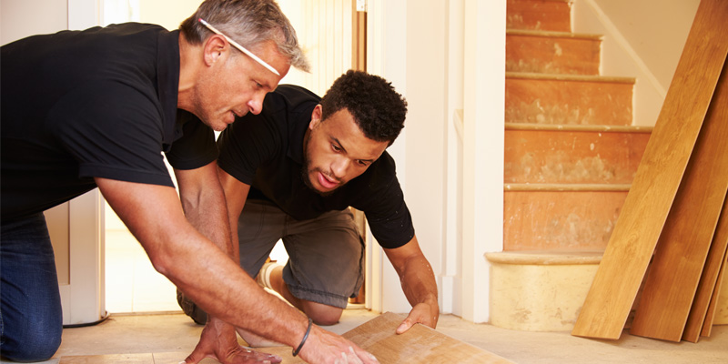 two fix-and-flip investors working together to lay new flooring