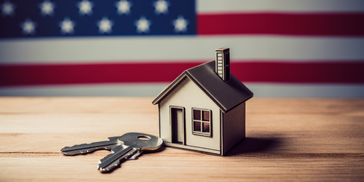 A wooden house model and keys, set against an American flag, symbolizing veterans' involvement in real estate investment.