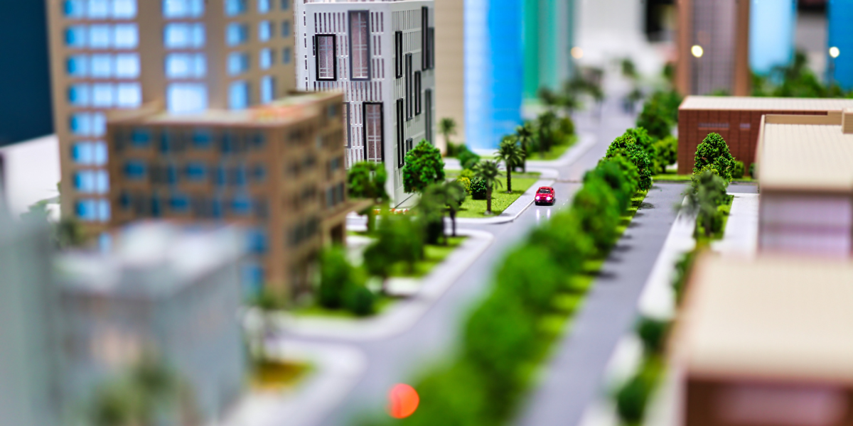  A miniature model of an urban development scene, depicting a vibrant cityscape with modern buildings, lush greenery along the streets, and a red car on the road, representing sustainable urbanization and the concept of transforming spaces through infill construction into efficient, green cities.