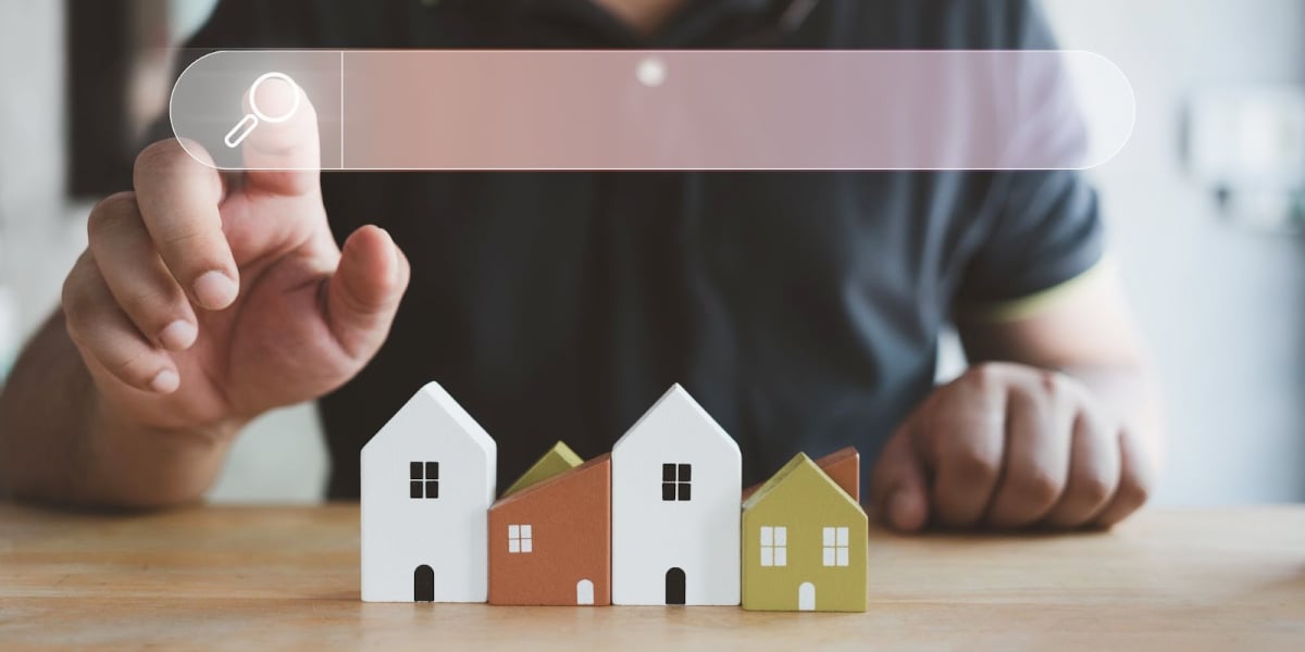 close up of a real estate investor searching the web with toy models of houses in front of him