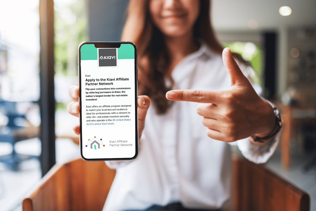 Woman pointing at phone showing Kiavi affiliate network application for real estate investors seeking financing.