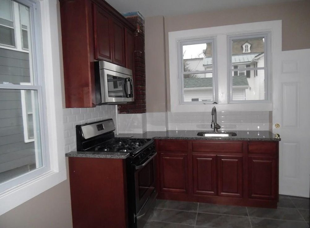 A recently renovated small kitchen with dark wood cabinets for a real estate investment.