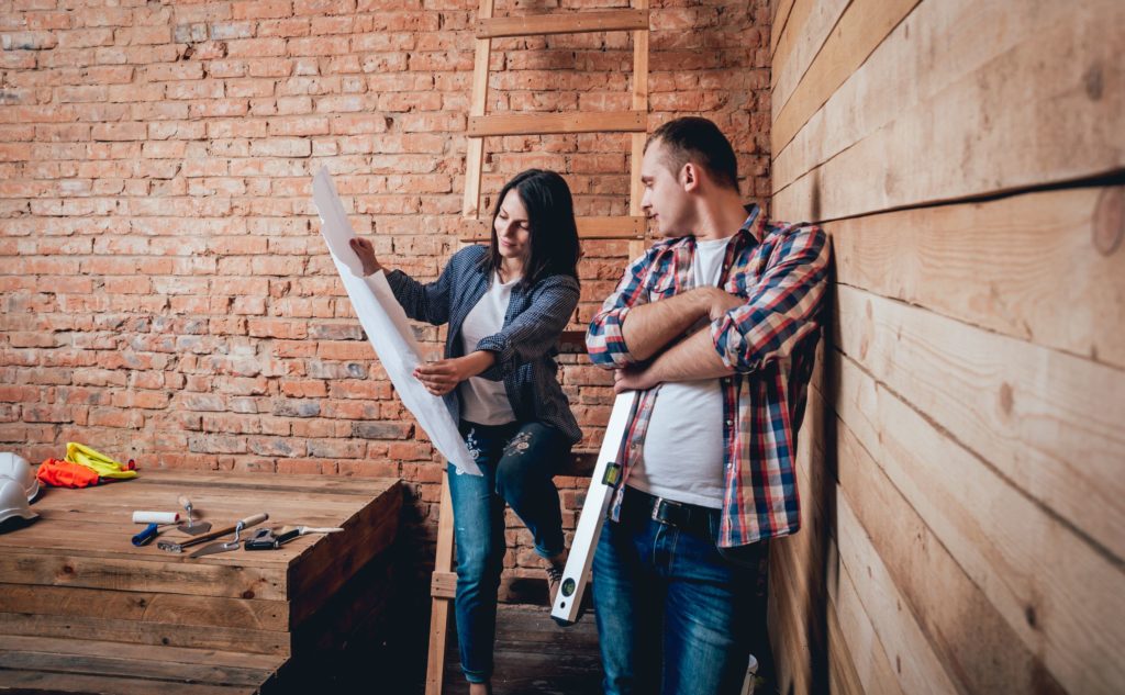 Two people in a renovated space looking over plans for a real estate investing property.