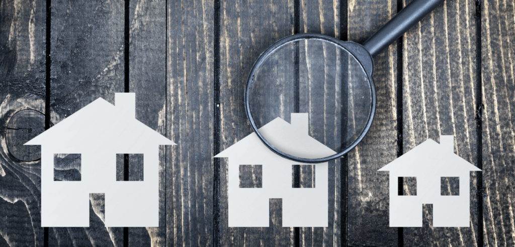 Houses on a wooden background with a magnifying glass.