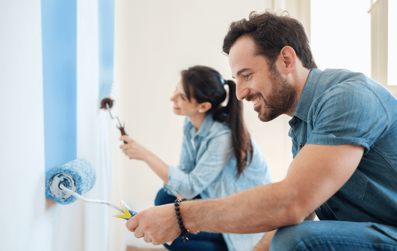 one male and one female real estate investor painting a wall as they rehab an investment property