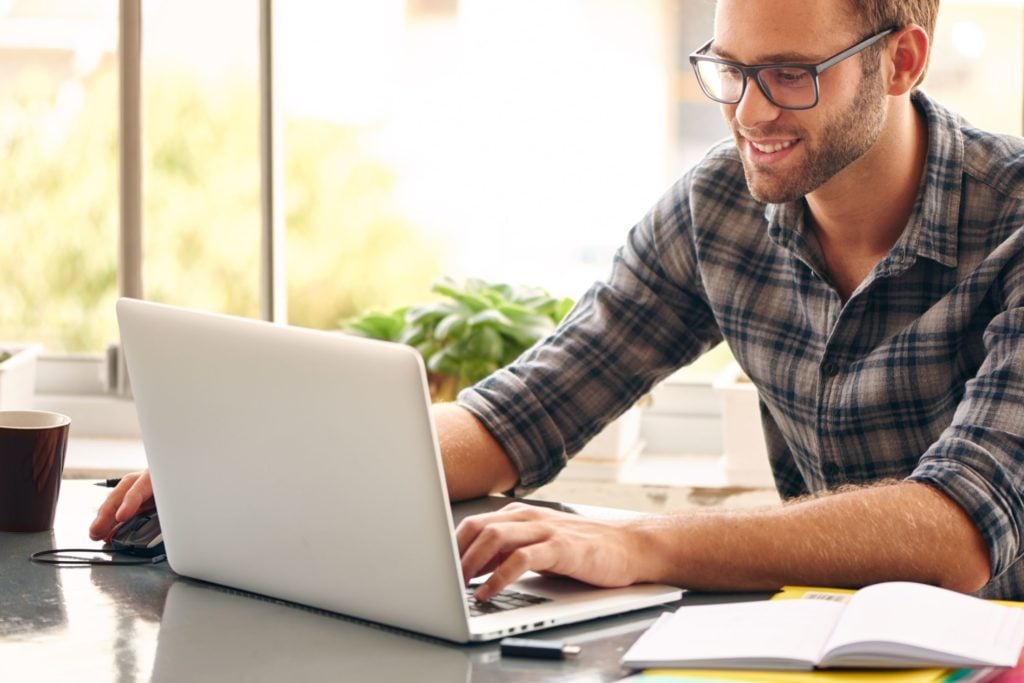 A man in plaid shirt on a laptop looking for a hard money lender.