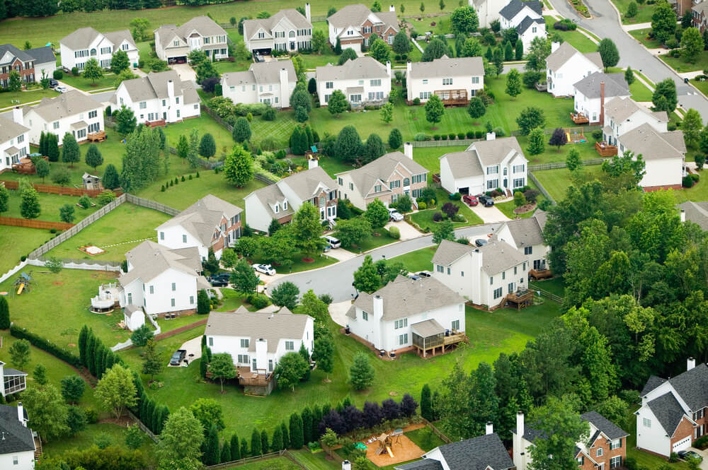 A bird's eye view of a beautiful neighborhood of big houses surrounded by green grass.