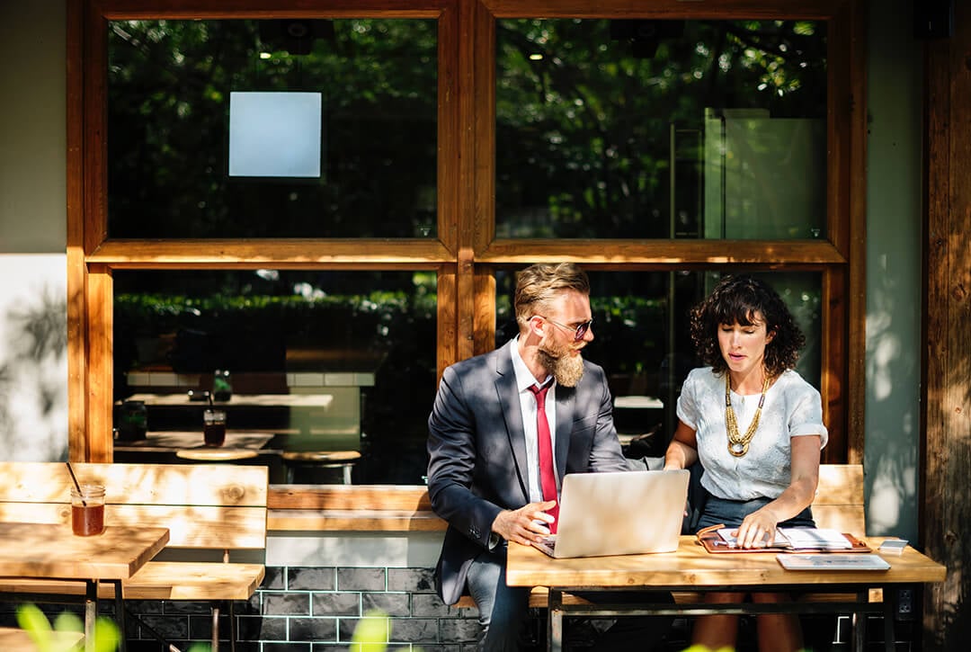 A real estate agent working with a real estate investor while they review a laptop