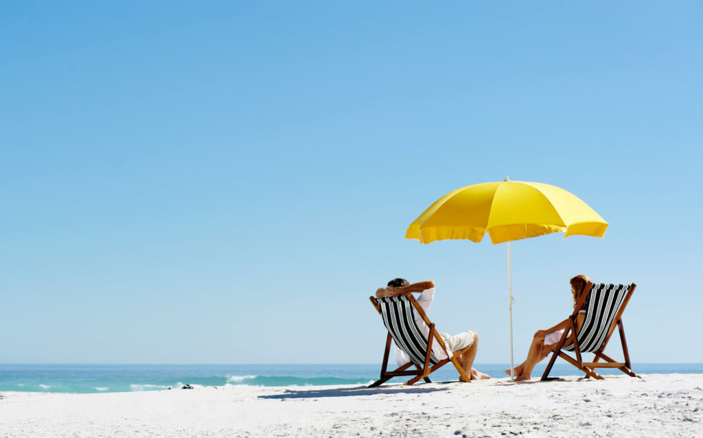 A beach scenery with two people in striped chairs under a yellow umbrella.