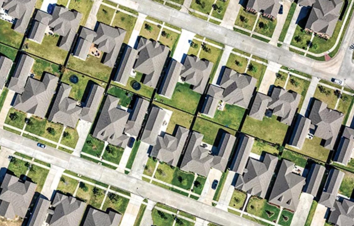 A bird's eye view of a clean, symmetrical neighborhood with big houses and green lawns.