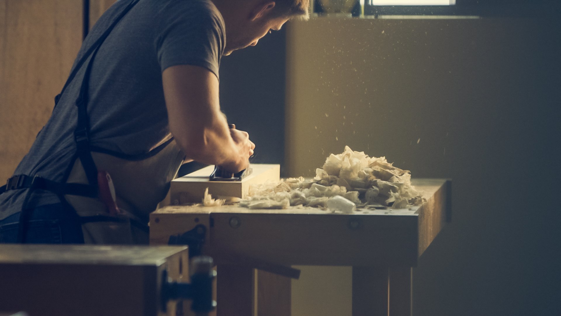 A man working on a piece for a house renovation at a work bench.