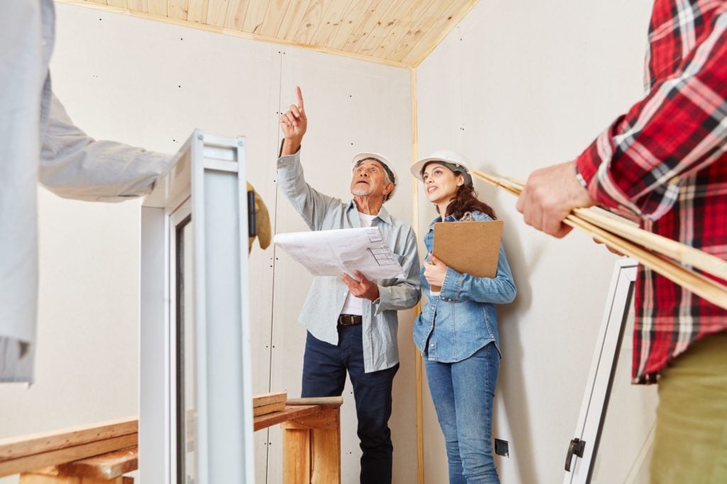 Two people looking over detail and pointing at walls at a renovation site.