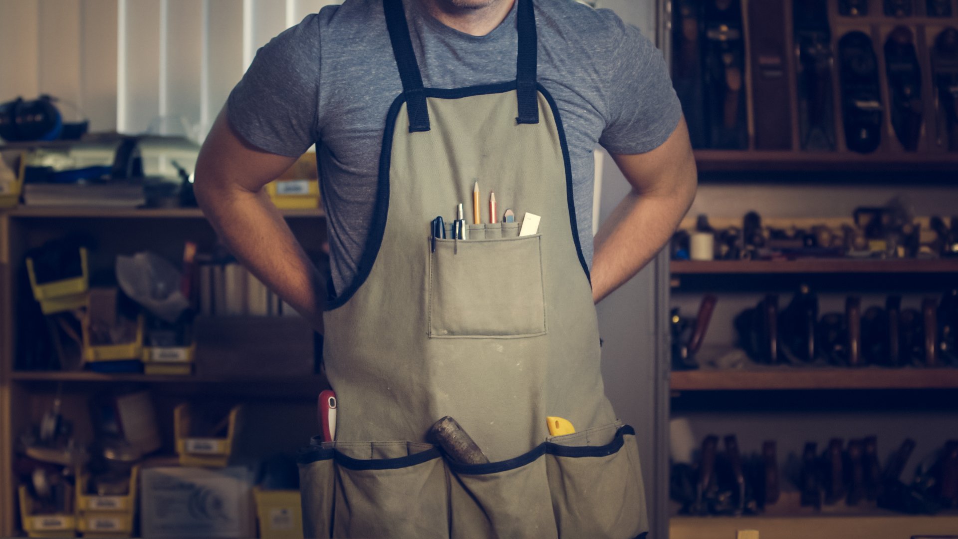 A man wearing a work apron with tools in it.