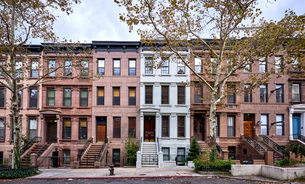 A block of brownstones with one white building.