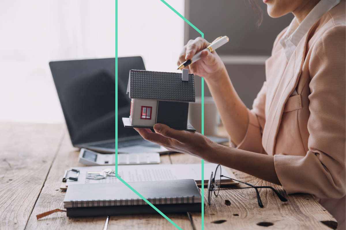 A real estate investor holding a small house model while reviewing notes and paperwork, planning their next BRRRR strategy investment with Kiavi.