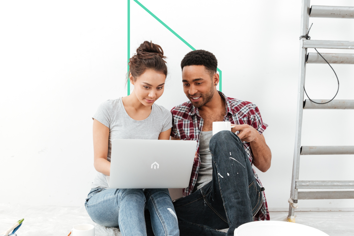 A real estate investor couple sitting on the floor, reviewing property options on a laptop, with a paint ladder in the background symbolizing fix-and-flip renovation plans.