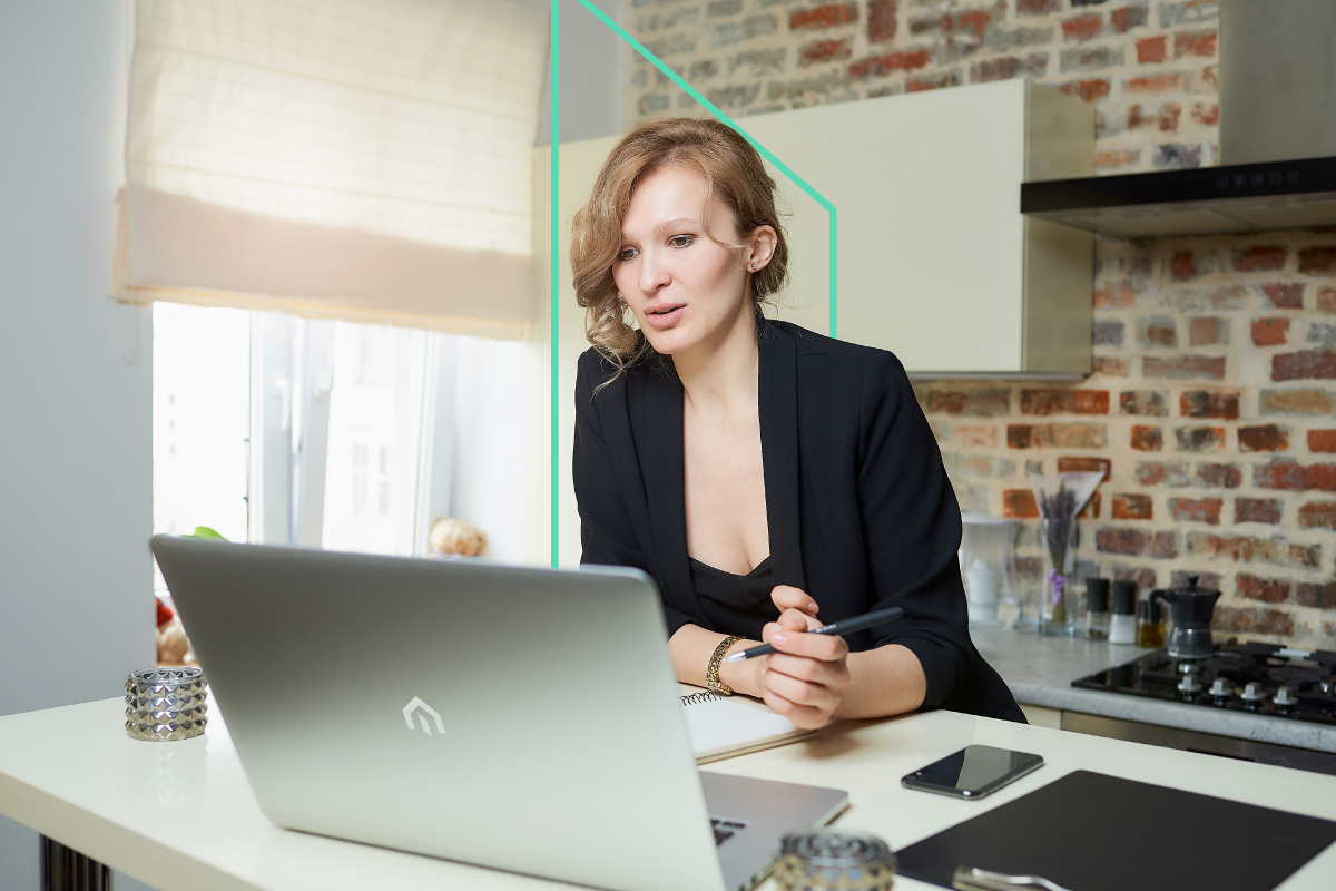 A real estate investor in a black blazer sits at a desk, focused on researching opportunities on a laptop, with a notebook and pen ready to strategize.
