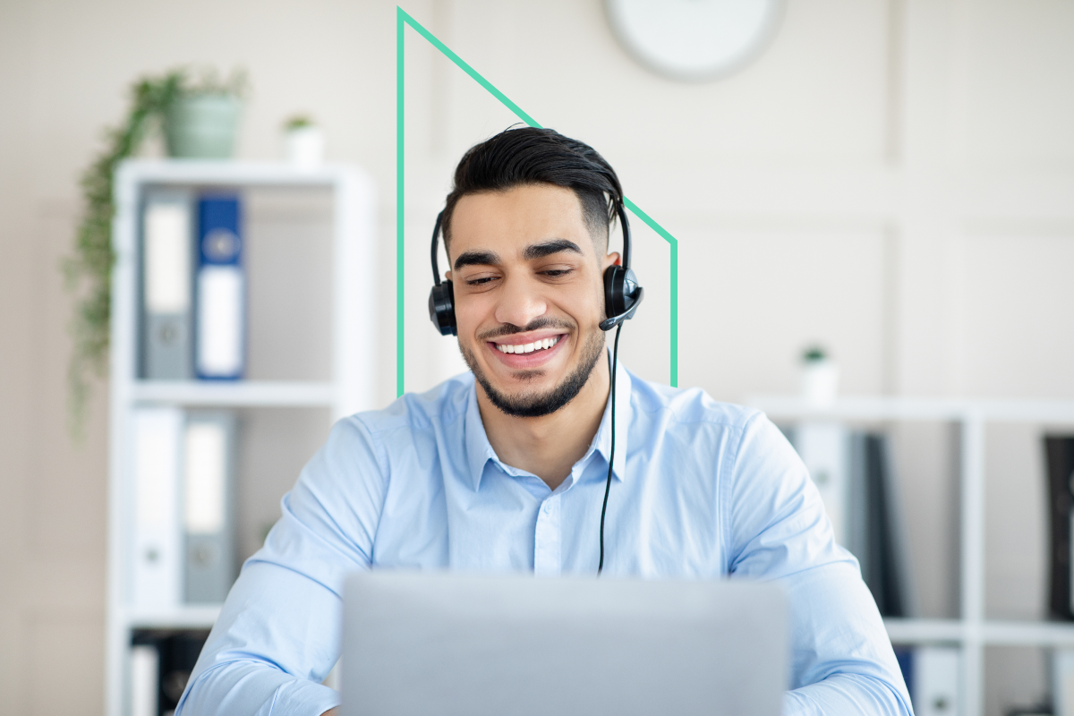 A Kiavi service representative, wearing a headset, smiles while assisting a real estate investor at their laptop in a bright office.