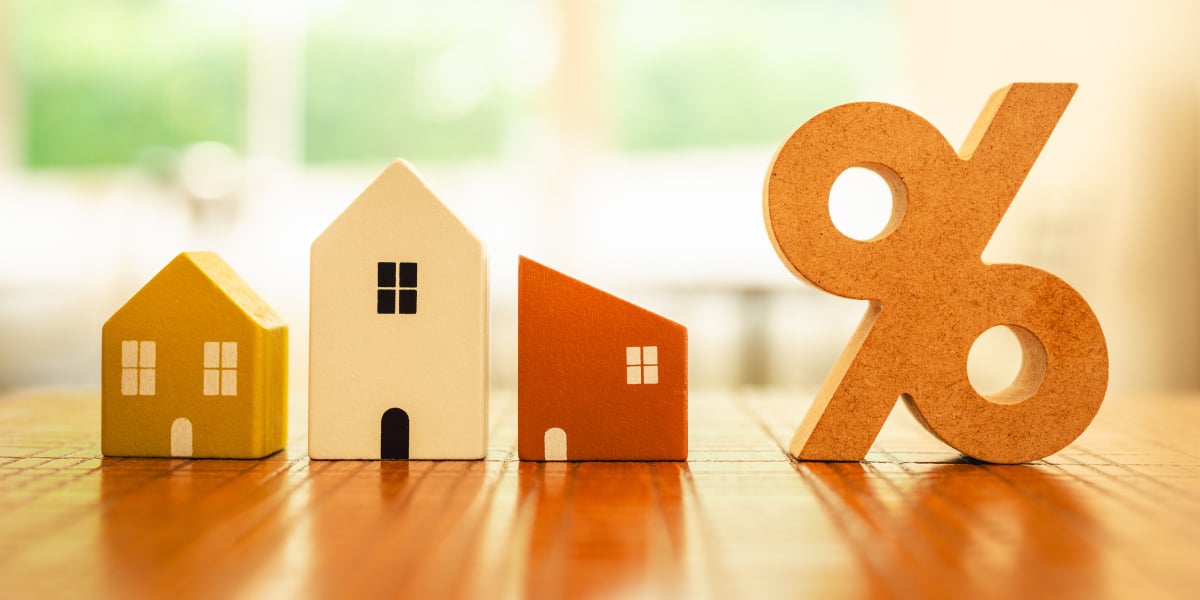 small wooden models of houses and a percent sign lined up on a table