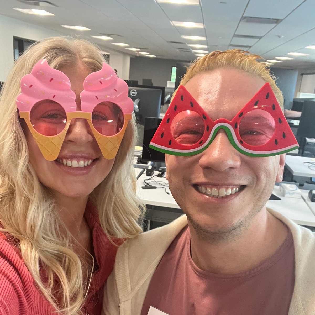 Two Kiavi employees smiling with ice cream and watermelon-shaped sunglasses in an office.
