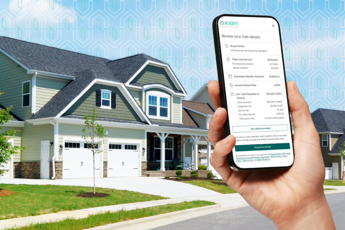 A real estate investor holding a phone showing Kiavi loan details in front of a gray and green investment property. 