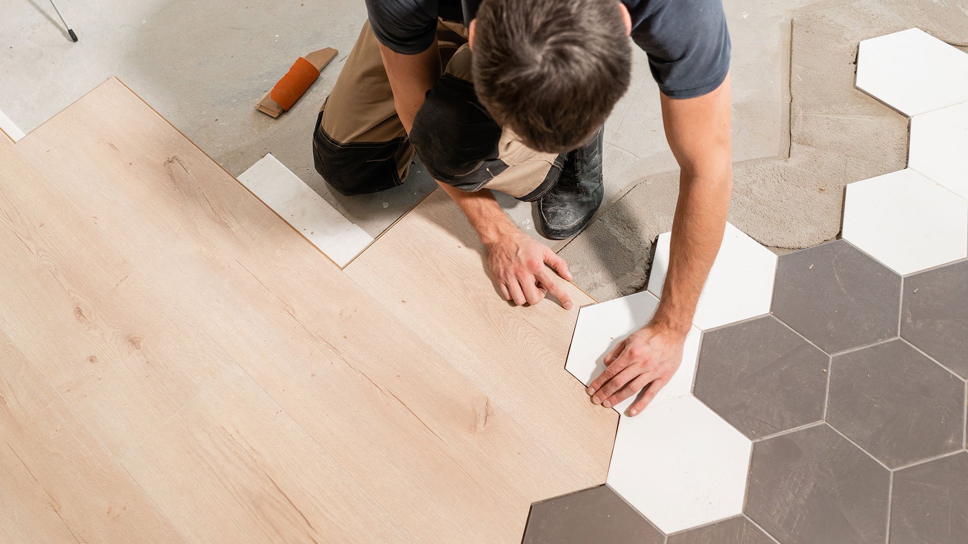 A real estate investor working on installing new hexagon shaped flooring in his real estate investment property