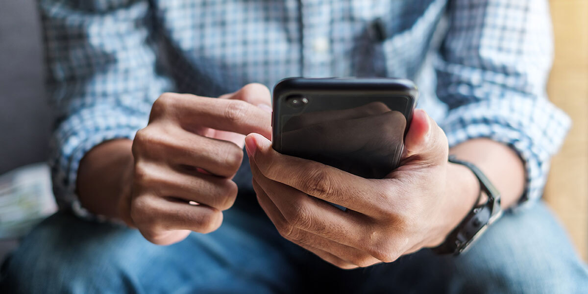 A man on his phone using various apps and finding deals for real estate investing