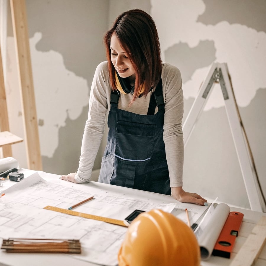 female real estate investor going over plans with tools on a workbench (1)