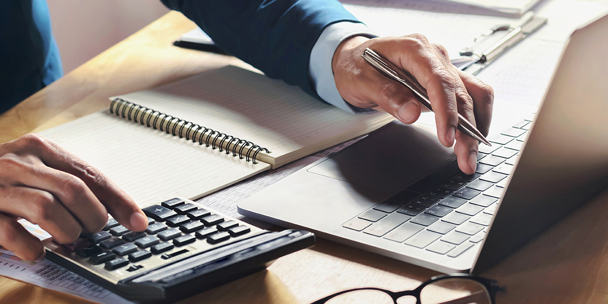 A man on a calculator and laptop looking up and finding deals