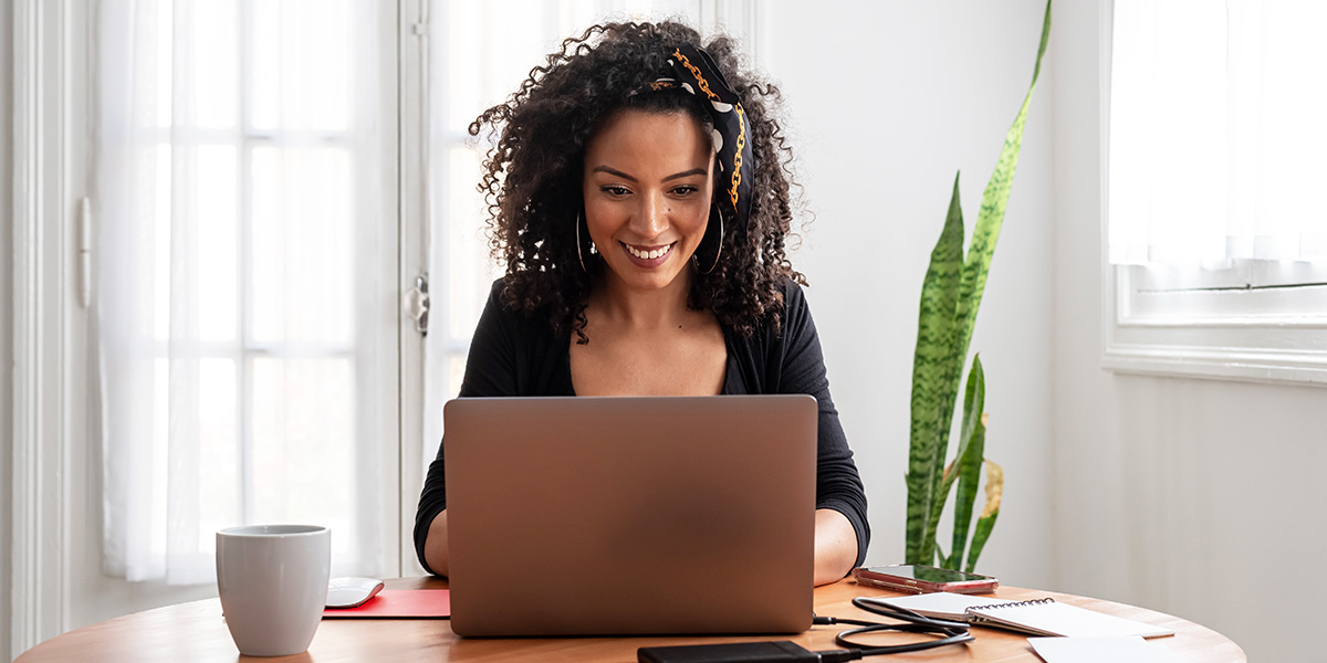 A woman smiling and working on her laptop while finding deals