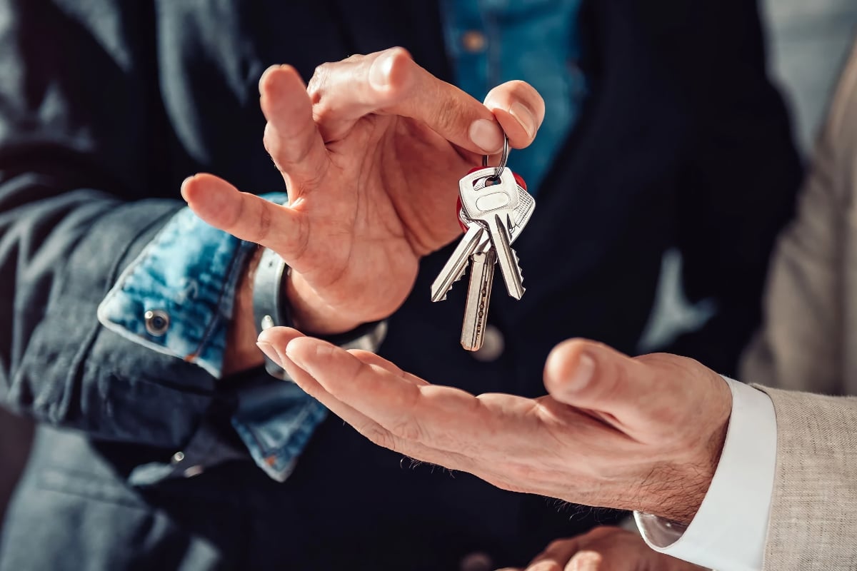 Two hands exchanging a set of rental property keys