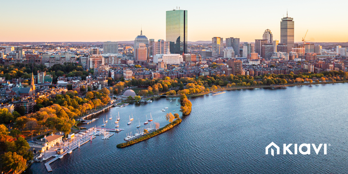 A high-quality aerial sunset photo of the Boston skyline and Charles River with the Kiavi logo in the bottom right corner.