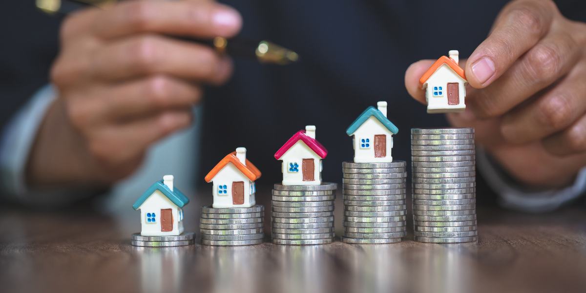 Small houses on growing coin stacks representing a BRRRR refinance with Kiavi real estate investment.