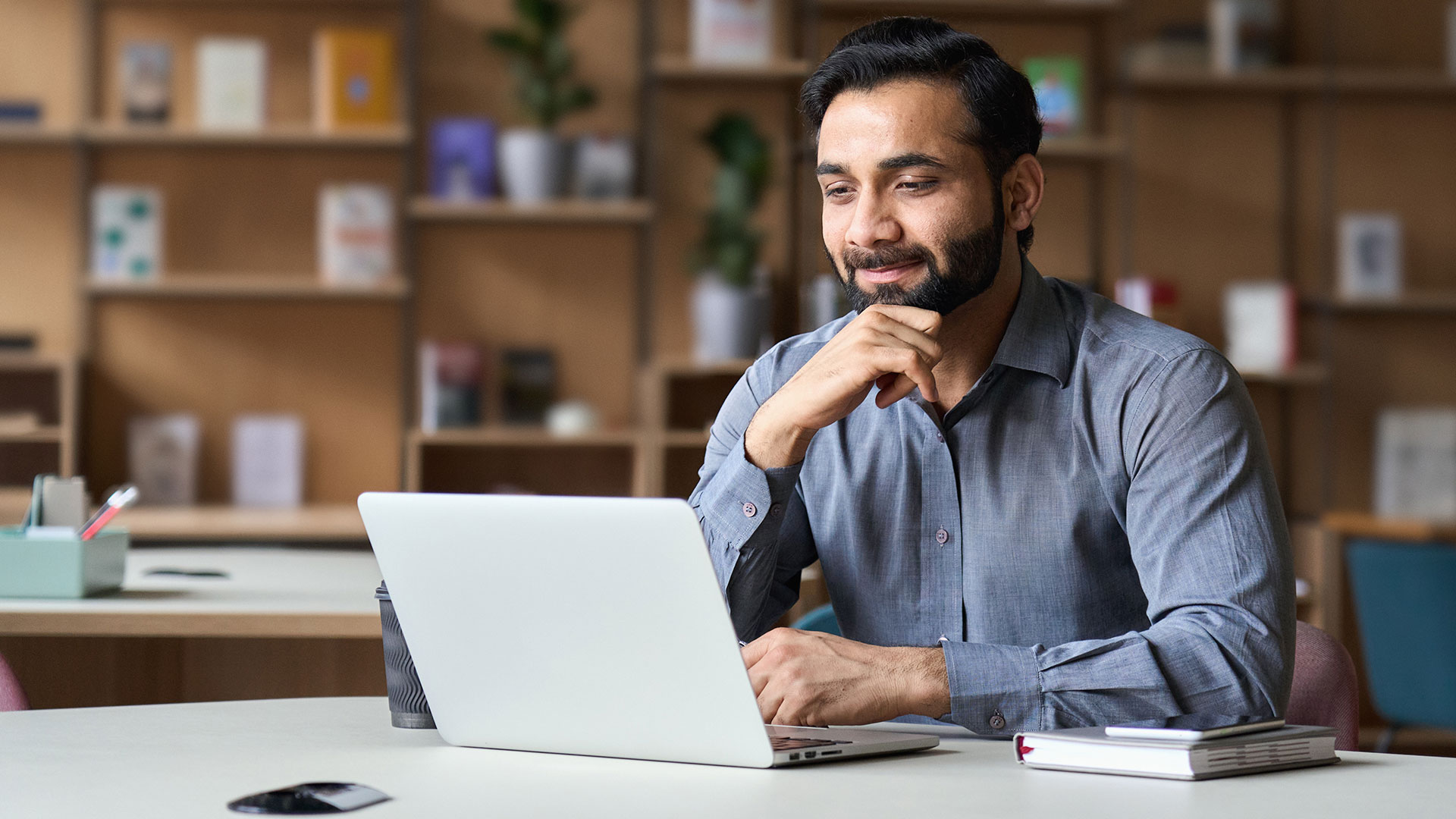 A real estate investor looking at his laptop in front of a bookcase
